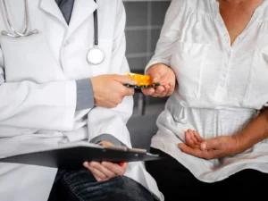 Doctor handing a blister pack of medication to a patient during a consultation